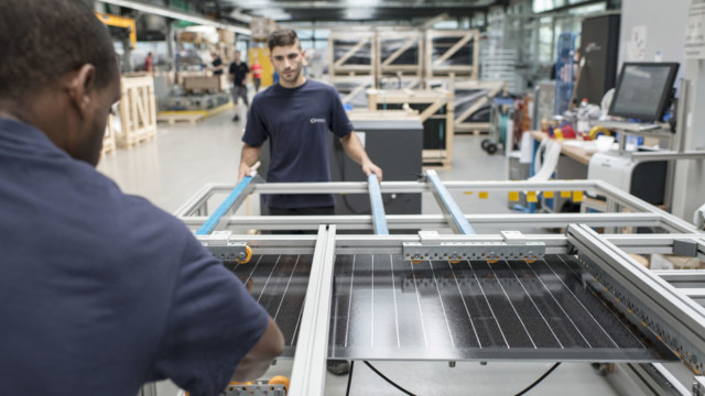 Zwei Mitarbeiter bereiten ein Solarmodul für die Verpackung vor, bei der Meyer Burger AG.